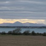 view from Ballyquintin Point across fields toward the Mournes