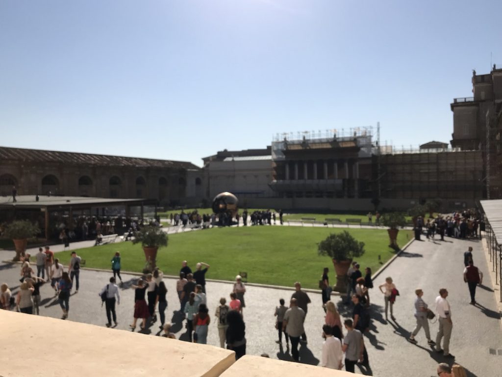 sunny, grassy courtyard with people milling around